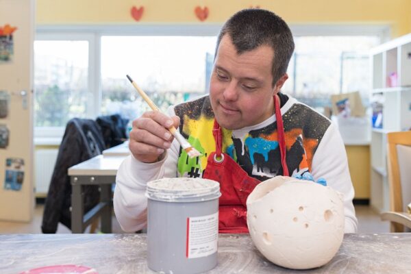 Cliënt beschildert keramiek tijdens dagbesteding